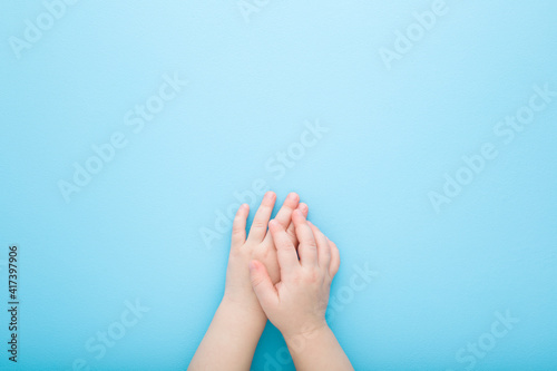 Baby hands on light blue table background. Pastel color. Closeup. Point of view shot. Empty place for text. Top down view.