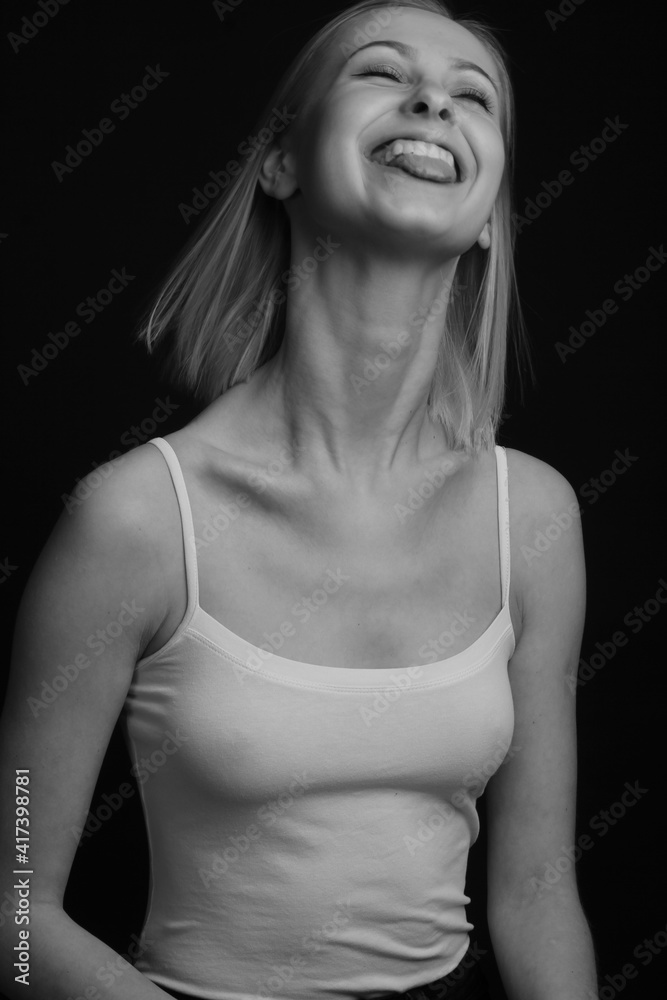 Black and white portrait blondes on a black background in a Tank Top With Thin Straps. laughs, rejoices, shows tongue Black and white portrait blondes on a black background in a Tank Top With Thin Straps. laughs, rejoices, shows tongue