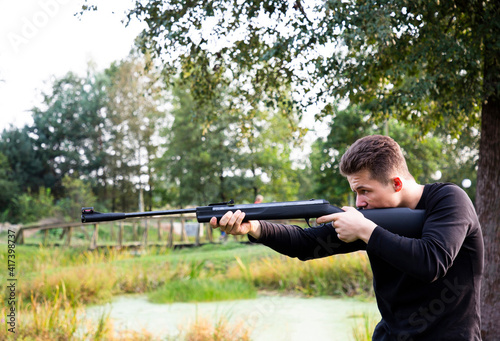Side view of young man aiming rifle