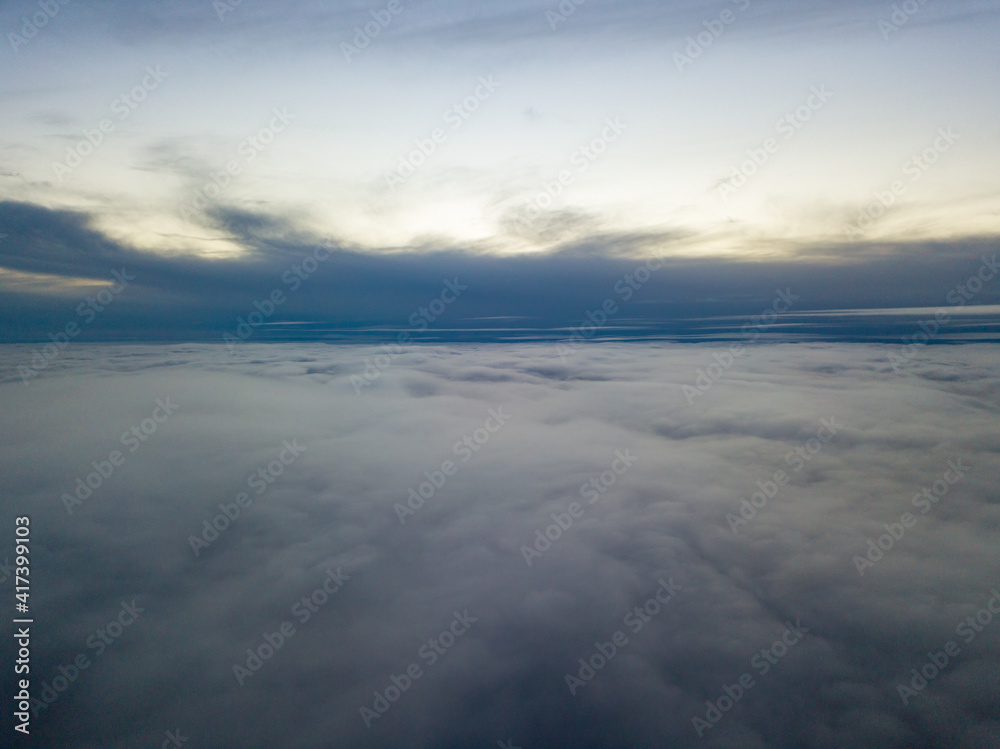 High flight above the clouds at sunset. Aerial view.