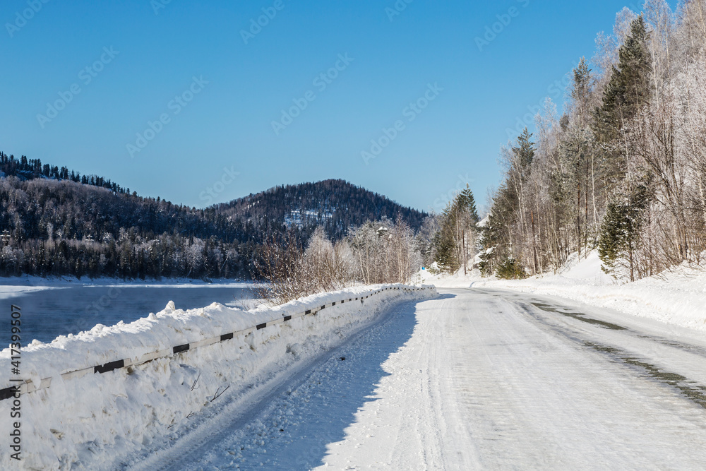 Snow-covered road along the Biya River. Russia, Altai Republic Snow-covered road along the Biya River. Russia, Altai Republic