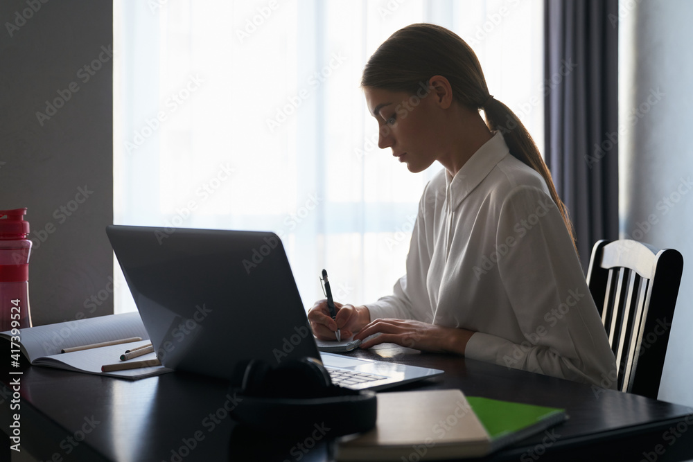 Focused woman sitting at table and working on laptop Focused woman sitting at table and working on laptop