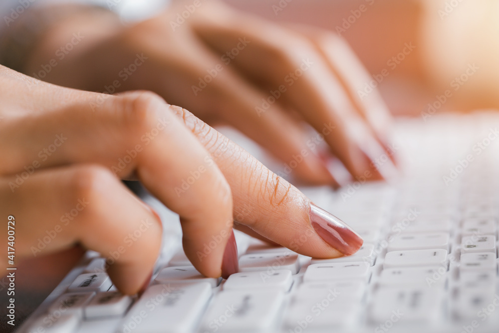 Close-up woman's hand working at home office typing on the keyboard.