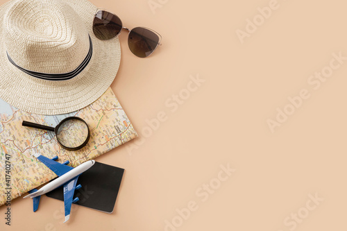 Straw hat  map  plane  passport  sunglasses and magnifying glass on pastel background. Summer holiday  vacation  travel concept. Flat lay  top view  copy space.