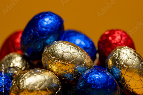 Pile of small colorful wrapped chocolate eastern eggs. Studio still life of season themed egg shaped treats.
