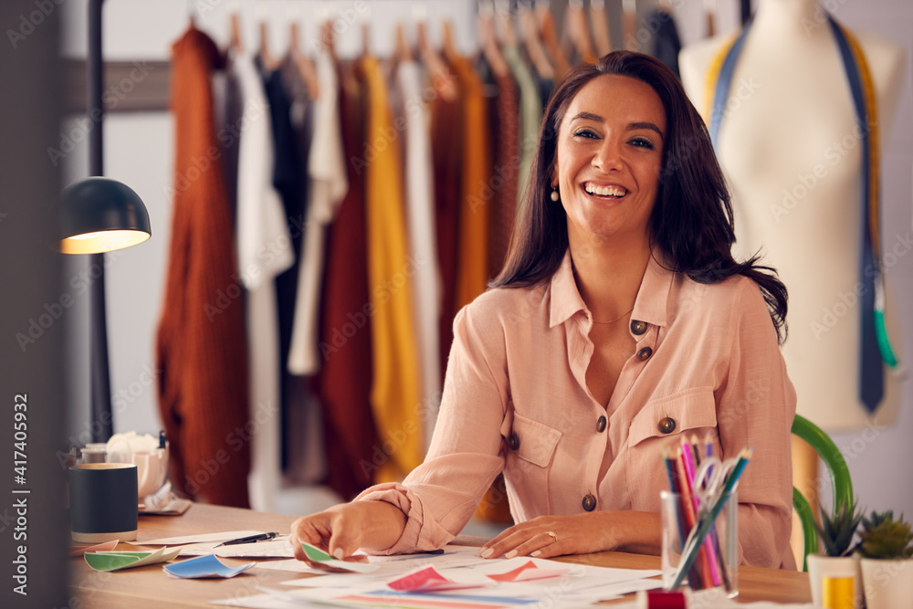 Fototapeta premium Portrait Of Female Fashion Designer In Studio Working On Sketches And Designs At Desk