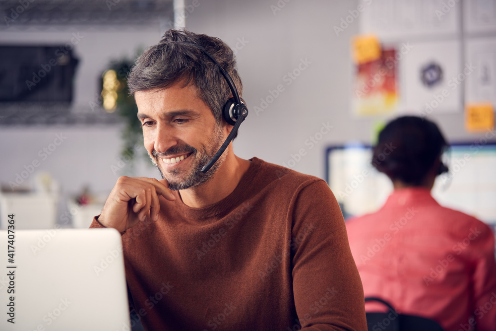 Fototapeta premium Business Team Wearing Telephone Headsets Talking To Callers In Customer Services Department