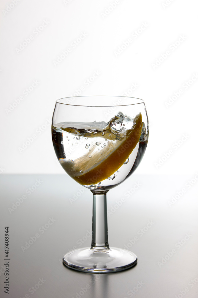 Slice of lemon drops in a glass of water. Water splash in a glass with lemon. Slice of lemon drops in a glass of water. Water splash in a glass with lemon.