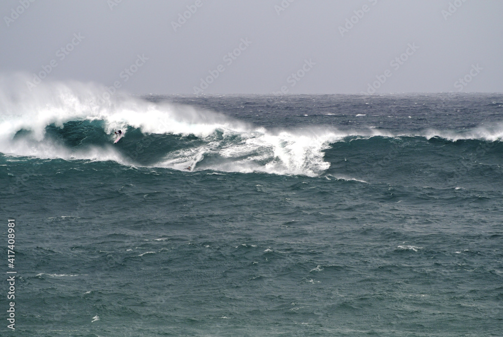 Gigantic waves, jet ski and a surfer