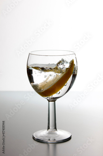 Slice of lemon drops in a glass of water. Water splash in a glass with lemon.