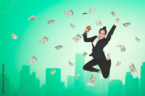 Businesswoman holding a trophy with falling money