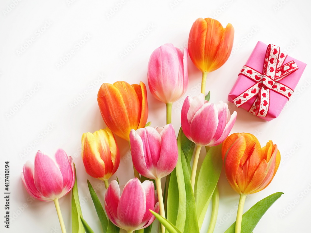 Naklejka premium Bouquet of multicolored tulips with pink gift box on white background