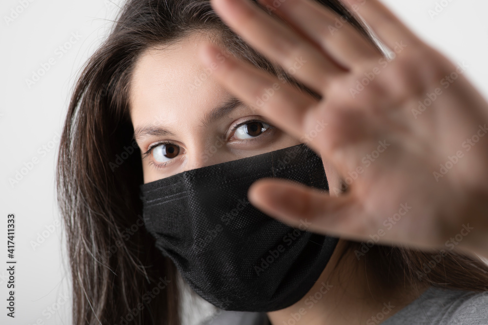 Portrait of young girl wearing black face mask showing her hand Portrait of young girl wearing black face mask showing her hand