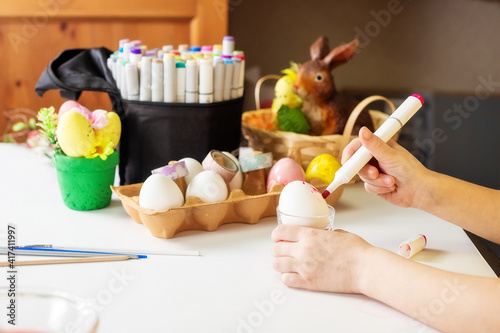 A close-up on the hands of a small girl 5 years old paints eggs