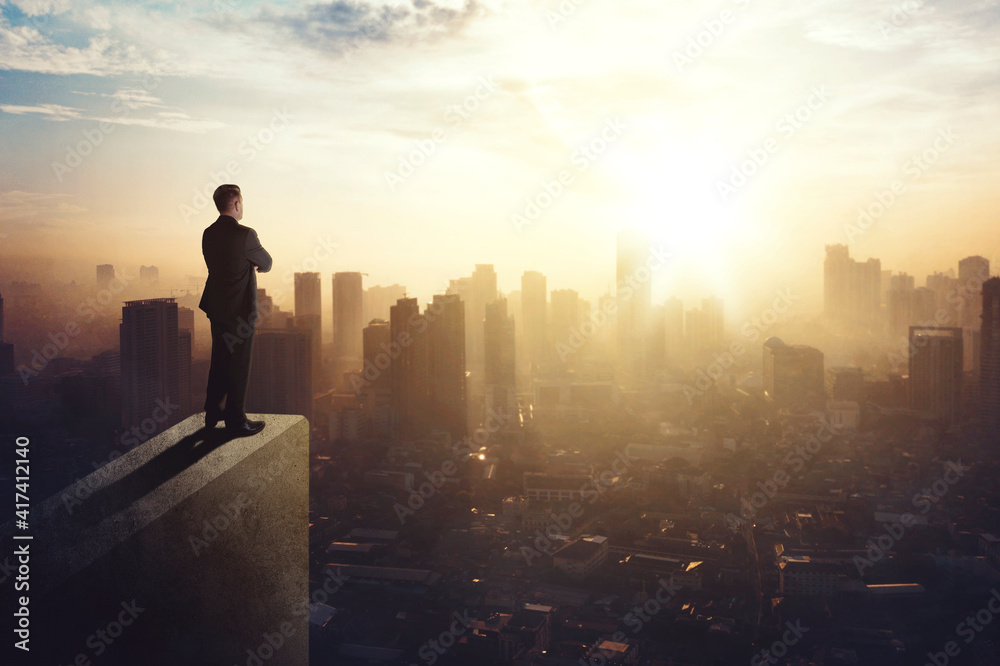 Confident businessman standing on building rooftop Confident businessman standing on building rooftop