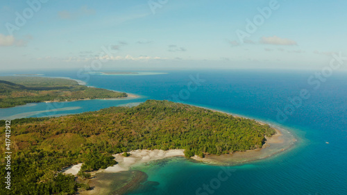 Coastline of tropical island Balabac covered with green forest against the blue sky with clouds and blue sea, aerial view. Seascape: Ocean and sky. Palawan, Philippines