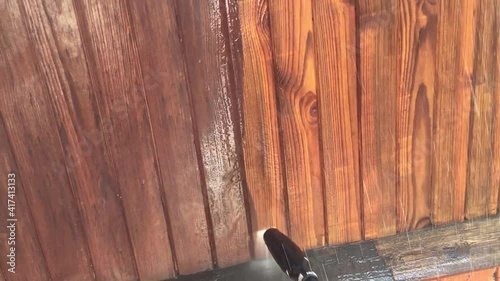 Washing the wooden facade with strong water pressure from pollution.