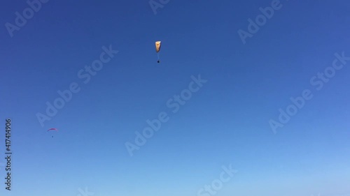 two skydivers are flying in the sky against a blue sky on a sunny, clear day.