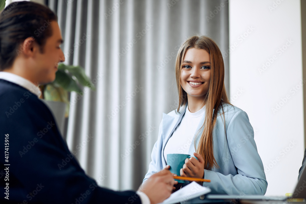 Beautiful female employee in suit is smiling during the job interview. Beautiful female employee in suit is smiling during the job interview.