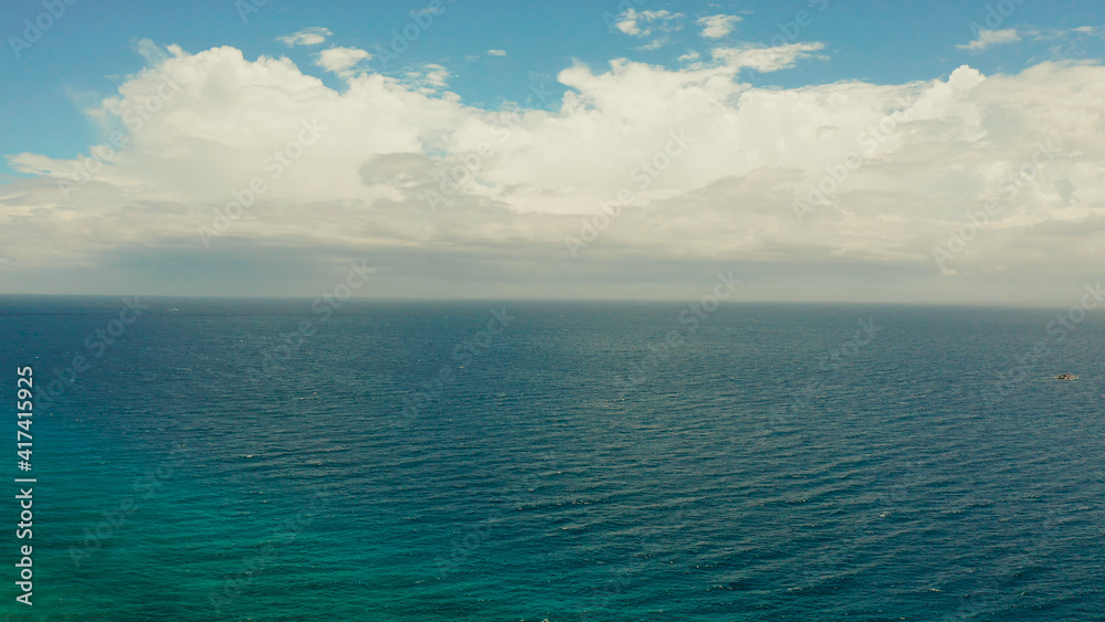 Sea surface with waves against the blue sky with clouds, aerial view. Water cloud horizon background. Blue sea water with small waves against sky.