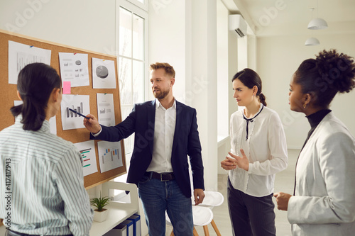 Business team analyzes sales graphs and charts, develops a new strategy, discussing work issues. Young project manager makes a suggestion or points out a mistake at the meeting. Concept of teamwork. photo