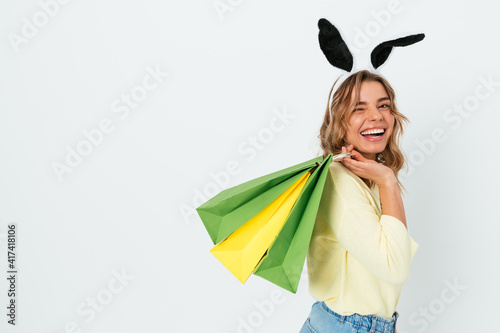 Canvas Print Happy young woman wearing easter bunny ears smiling holding shopping bags