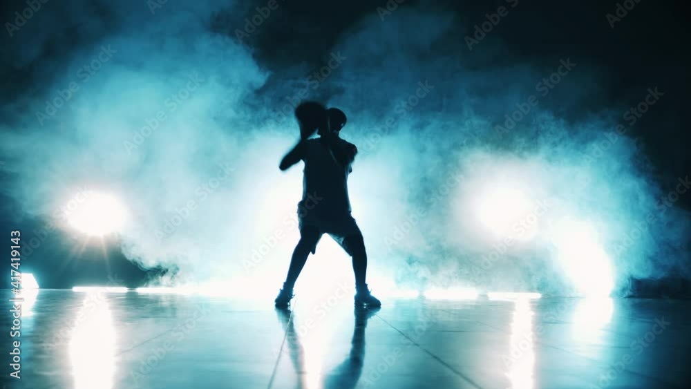 Dark room with clouds of smoke and a man throwing a basketball ball Dark room with clouds of smoke and a man throwing a basketball ball