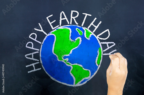 Hands draw a globe and write Happy Earth Day text