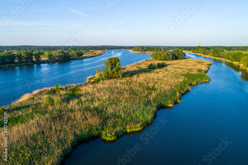The Odra River in Poland, in a section of the Śląskie Voivodeship, photographed during the golden hour. The beautiful blue color of the river and shades of yellow and green on land. 