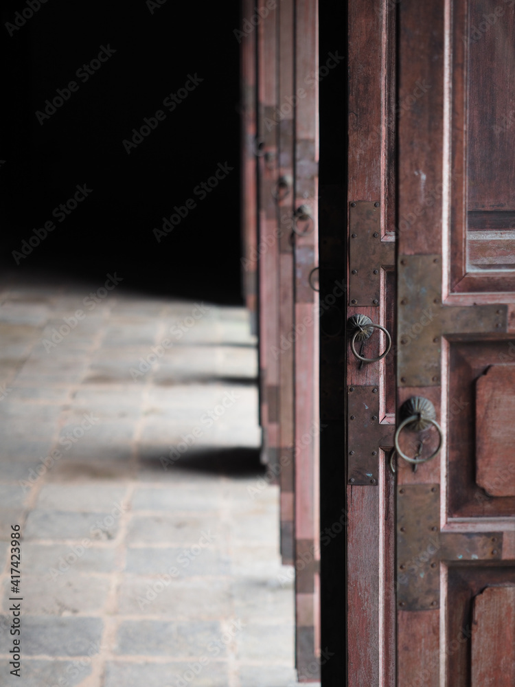 Light coming to the temple through opened wooden ancient door.