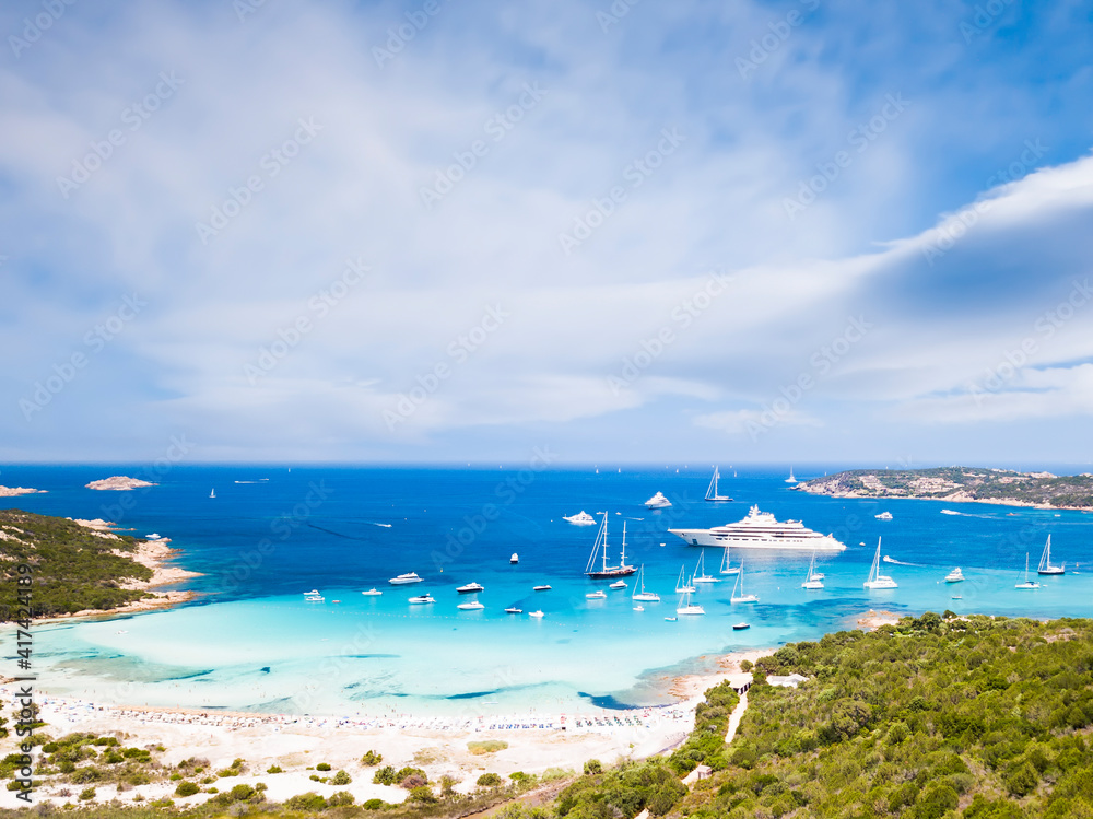 View from above, stunning aerial view of the Grande Pevero beach with boats and luxury yachts sailing on a turquoise, clear water. Sardinia, Italy.