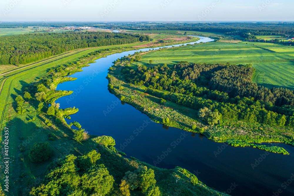 The majestic river meanders between green areas. The blue color contrasts with the greens of fields and meadows.