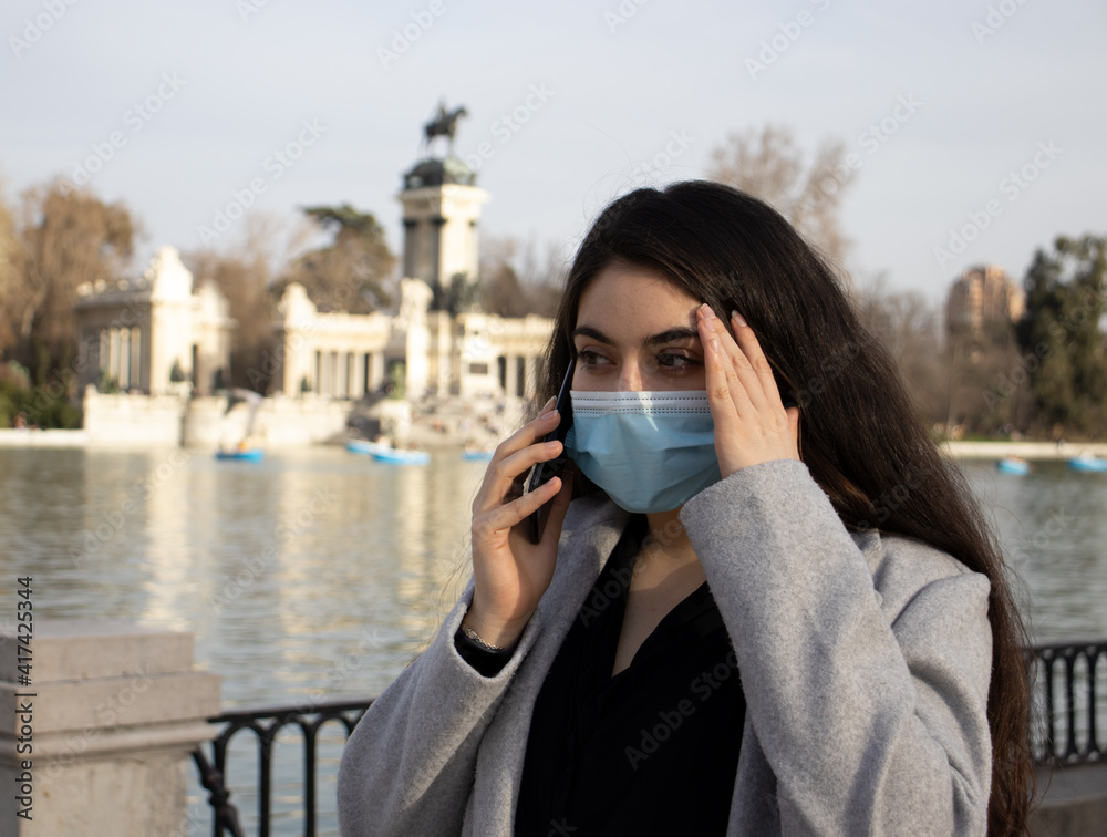 woman with face mask worried while talking on mobile. (receiving bad news)