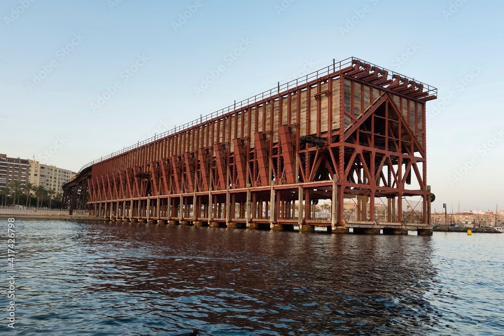 View at sunset of an iron ore loading dock built in 1904 by The Alquife Mines and Railway Company Limited, known as Cable Ingles, an example of engineering work of iron architecture - obrazy, fototapety, plakaty 
