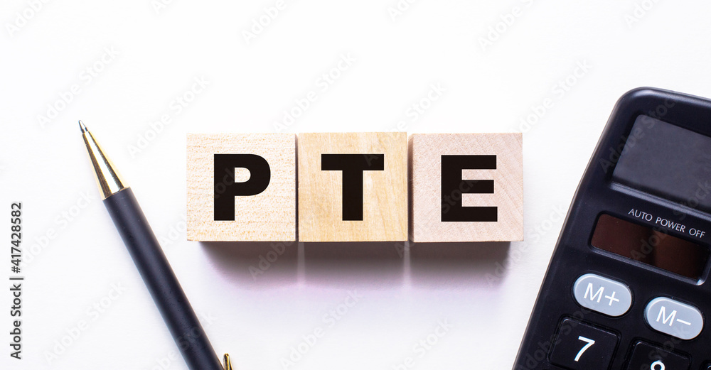 The word PTE is written on wooden cubes between a pen and a calculator on a light background. The word PTE is written on wooden cubes between a pen and a calculator on a light background.
