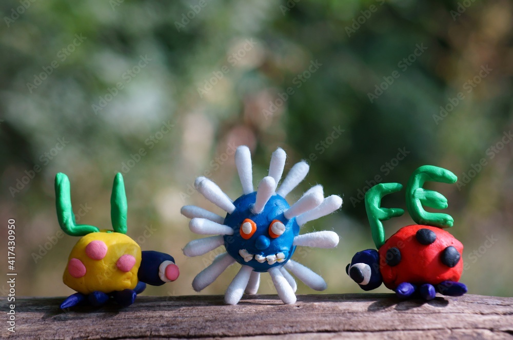 Figurines of two ladybirds made of plasticine. The figures are placed opposite each other. Between them the figure of the virus. Next to it is the inscription life.