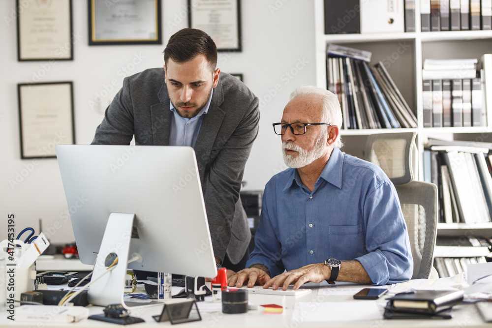 Young assistant explaining to his manager how to solve the problem. Working day at the office. Young assistant explaining to his manager how to solve the problem. Working day at the office.