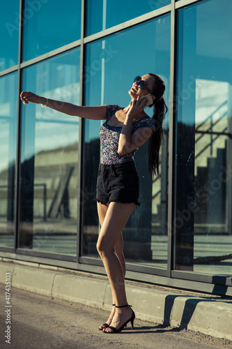 Very sexy girl talking on the phone.girl with long legs near a glass structure.Very sexy girl talking on the phone.