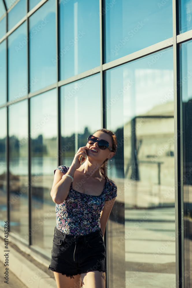 Sexy girl talking on the phone near the glass building Sexy girl talking on the phone near the glass building