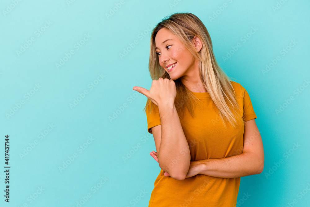 Young mixed race woman isolated on blue background points with thumb finger away, laughing and carefree. Young mixed race woman isolated on blue background points with thumb finger away, laughing and carefree.
