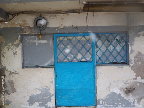 Fototapeta Naklejka Na Ścianę i Meble -  Turquoise metallic door in a ramshackle building, Greece