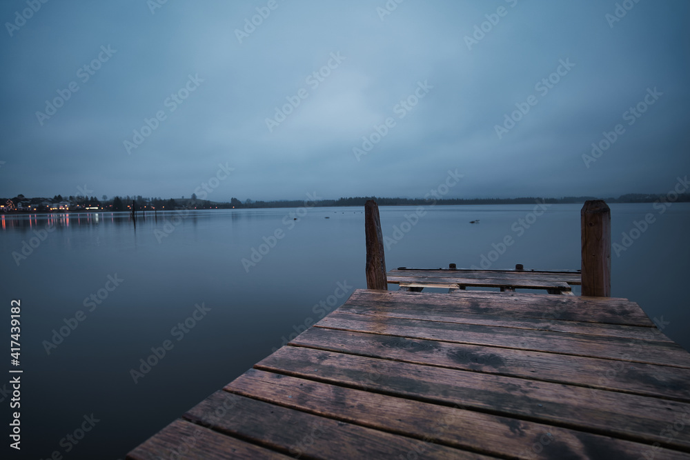 Wooden pier on the blue lake in the morning with a cloudy sky Wooden pier on the blue lake in the morning with a cloudy sky