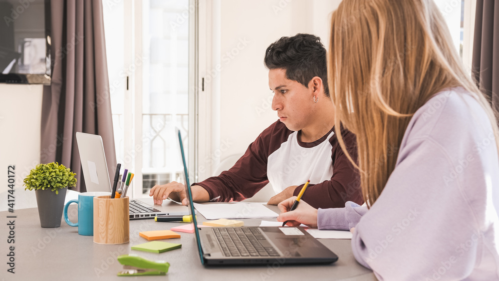 Young couple using laptops while working remote from home. Business and home office concept. Young couple using laptops while working remote from home. Business and home office concept.