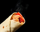 Classic tortilla wrap roll with grilled crispy chicken or turkey and vegetables, tomato, paprika pepper with steam smoke on black background