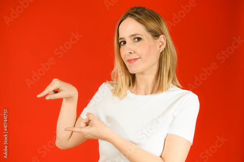 Young woman over isolated red background pointing fingers to the side