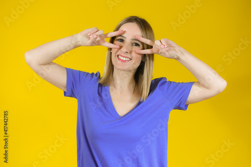 Beautiful young woman happy and excited expressing winning gesture. Successful pretty woman celebrating victory, triumphant over yellow background