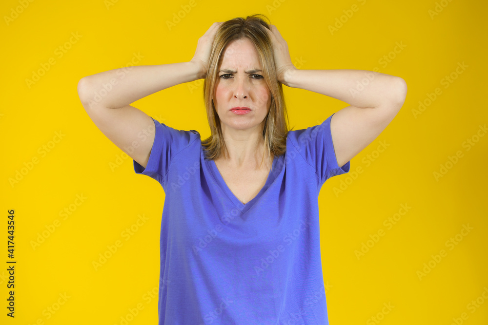 Shocked amazed young woman with hands on head standing over yellow background Shocked amazed young woman with hands on head standing over yellow background