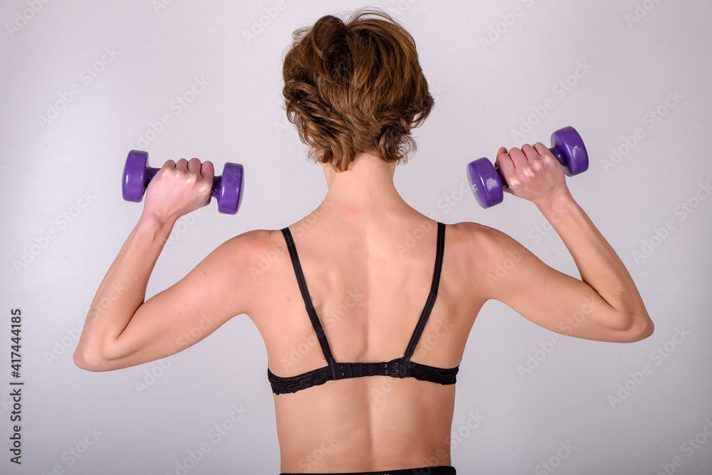 girl exercise with dumbbell on gray background girl exercise with dumbbell on gray background