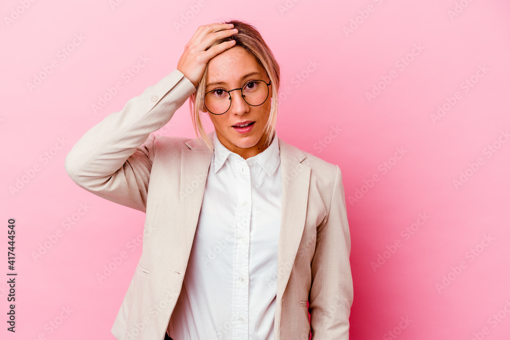 Young caucasian mixed race business woman isolated on pink background being shocked, she has remembered important meeting.