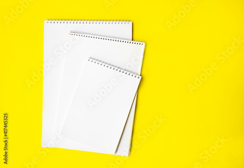 three white notepads lie on a yellow background